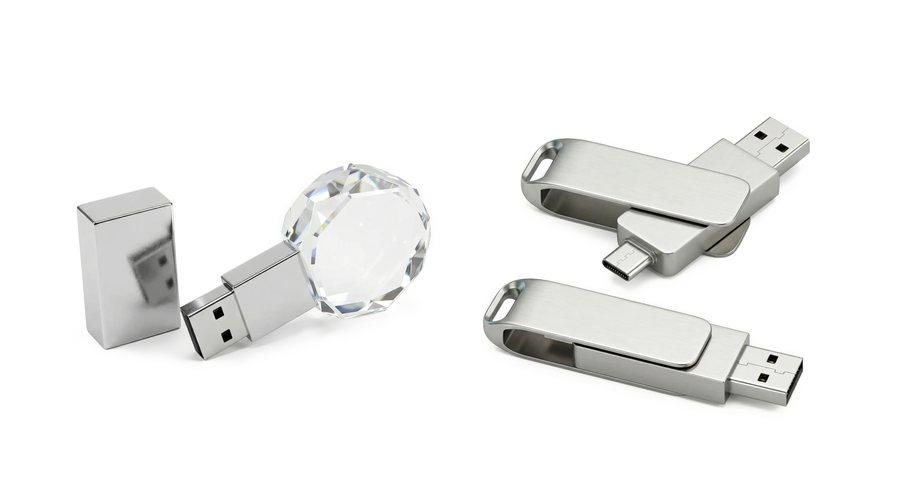 A crystal USB drive and two metal swivel flash drives.