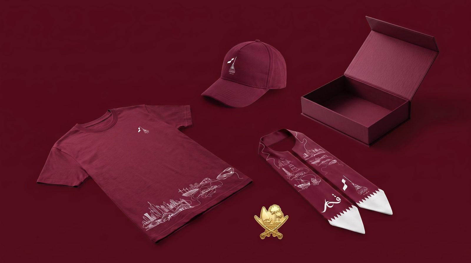 The Fakhr Qatar set on deep maroon: heritage T-shirt, cap, scarf, gold badge and magnetic-closure box.